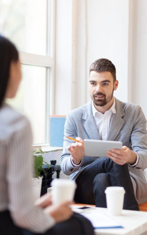 Confident employee with touchpad talking to his co-worker