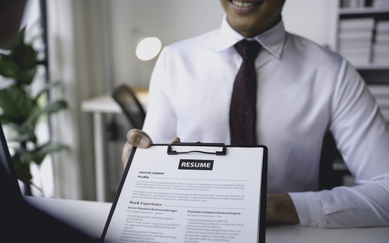 Smiling businessman holding resume giving to human resources manager in job interview
