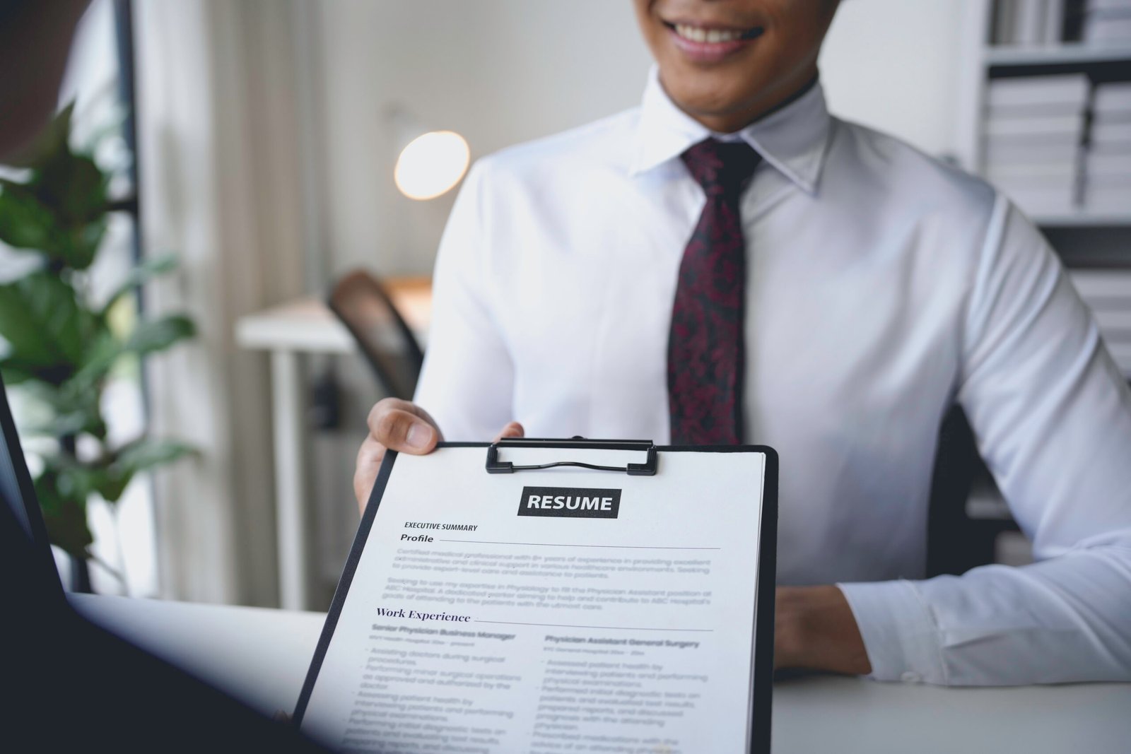 Smiling businessman holding resume giving to human resources manager in job interview